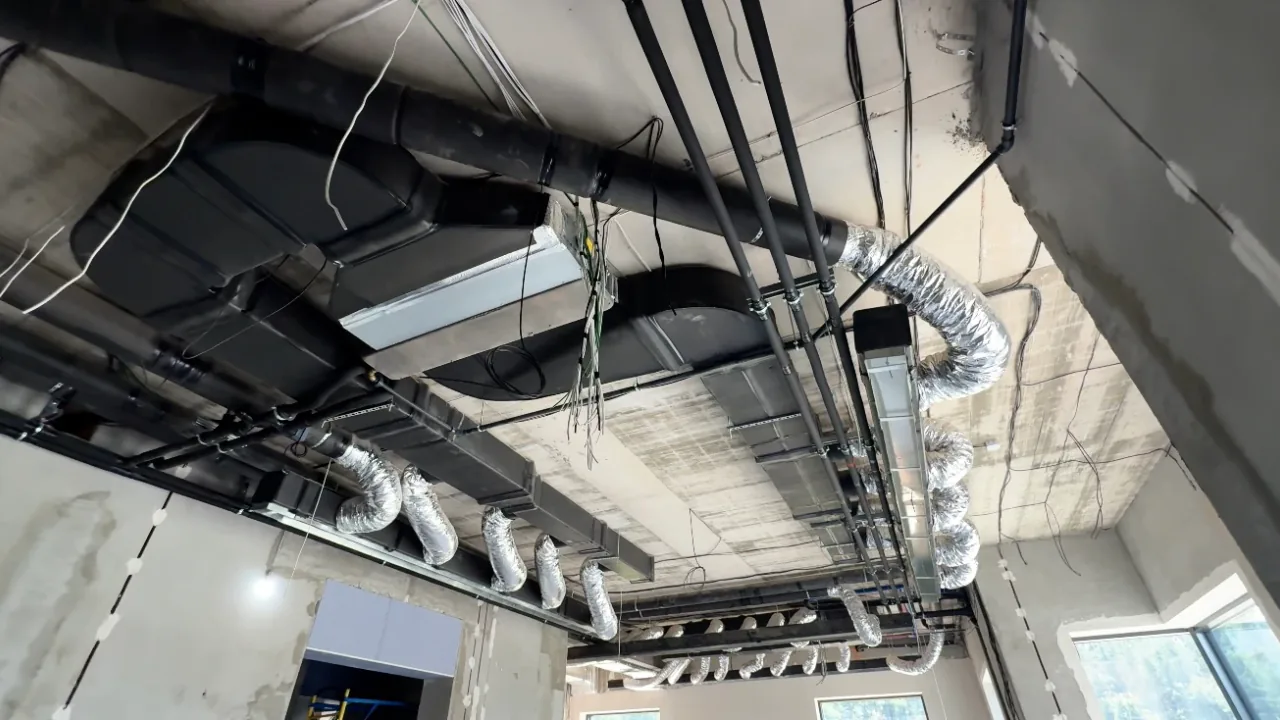 Розгалужена система повітропроводів із підключенням центрального блоку вентиляції під перекриттям будинку.