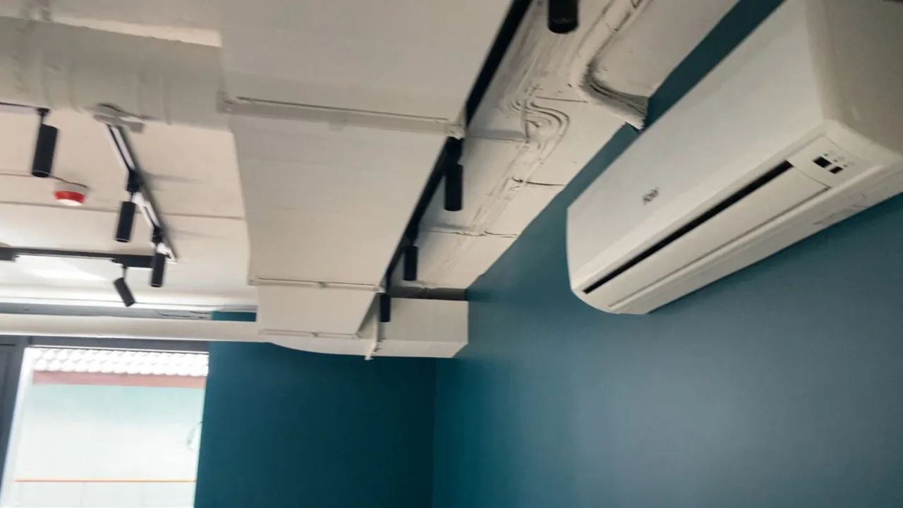 Стеля в офісі з білими припливними дифузорами та круглими повітропроводами системи вентиляції.