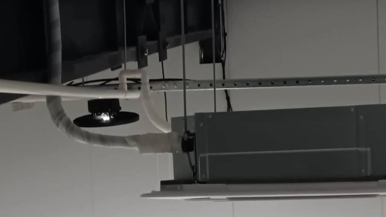 Фахівець Ventall на риштуванні виконує монтаж великого канального блоку кондиціонування, підвішеного до бетонної стелі.