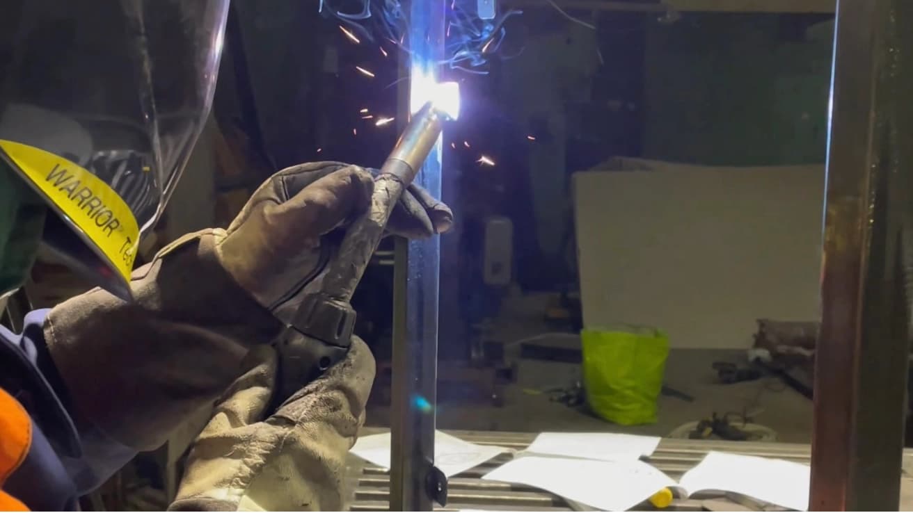 Фахівець виконує зварювання металевого елемента під час збірки вентиляційного обладнання.